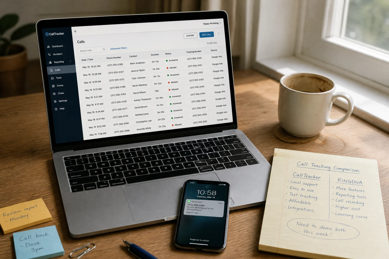 Laptop showing an answering service call-log dashboard on a desk with a smartphone, coffee mug, and handwritten comparison notes.