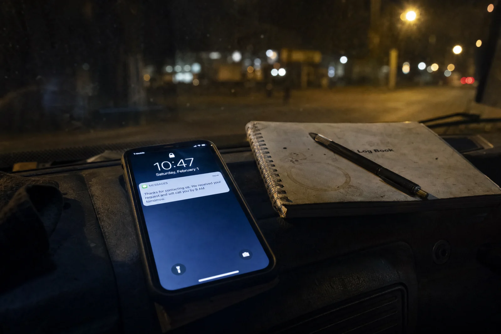 Smartphone on truck dashboard at night displaying automated text message response from service company.