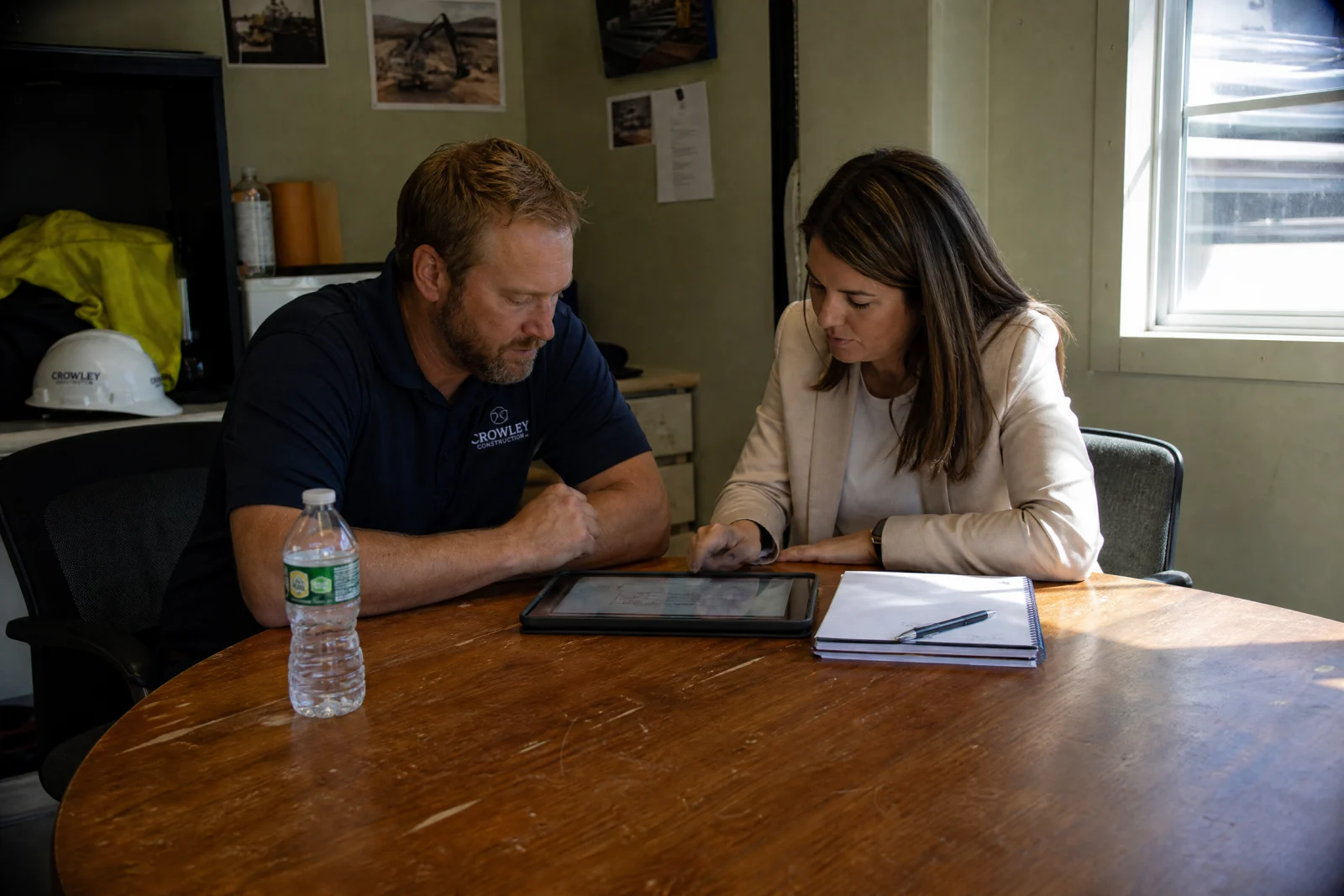 Manager and field worker reviewing tablet together at wooden table during training session on new system.